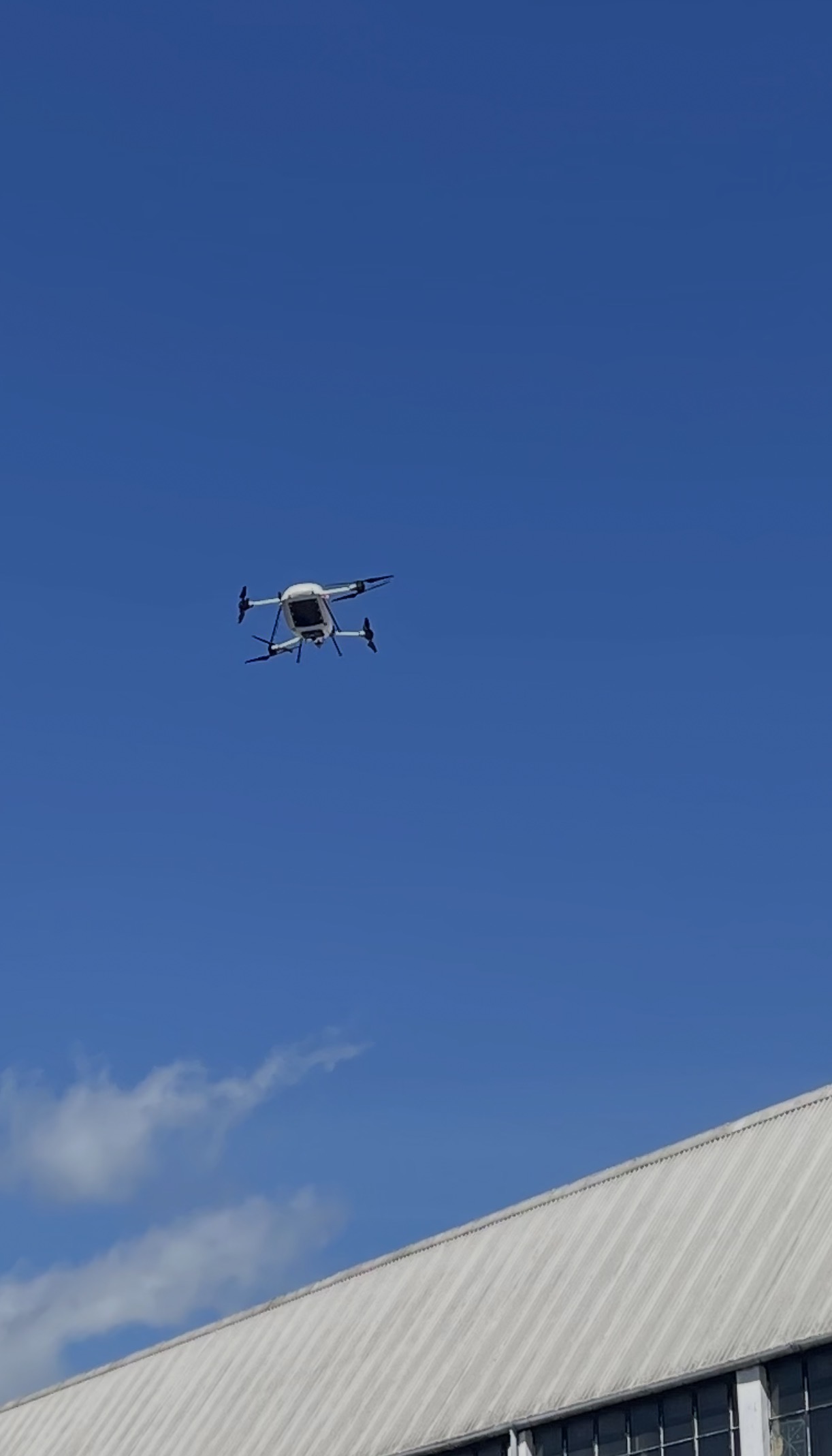 A Manna delivery drone overhead, photographed from a residential garden